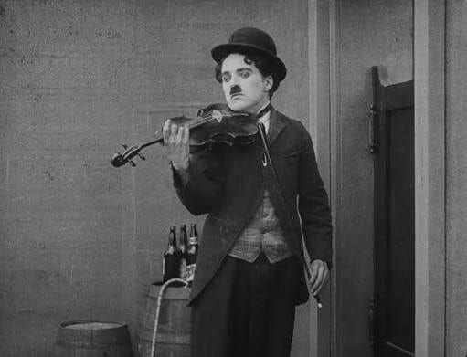 Charlie Chaplin an der Violine in einer Szene aus „The Vagabond“ (1916): als Autodidakt spielte er Geige und komponierte später die Musik zu seinen Filmen.