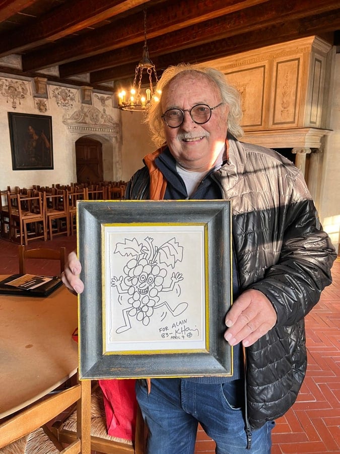Alain Parisod und „Le Pot joyeux“, die Cuvée 2022 zum vierzigsten Jahrestag, deren Etikett die Zeichnung aufnimmt. Aufnahme erschienen in Le Courrier im April 2023.