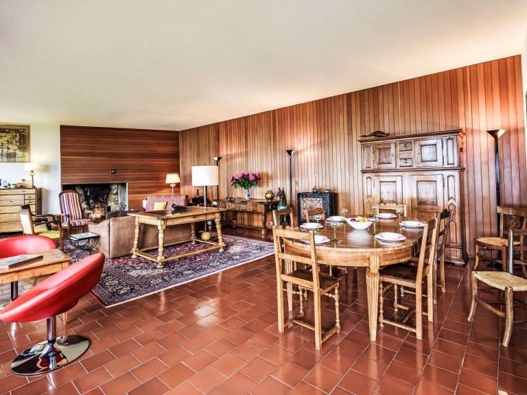 Der grosse holzgetäfelte Wohnraum mit Kamin, der in das Esszimmer übergeht.