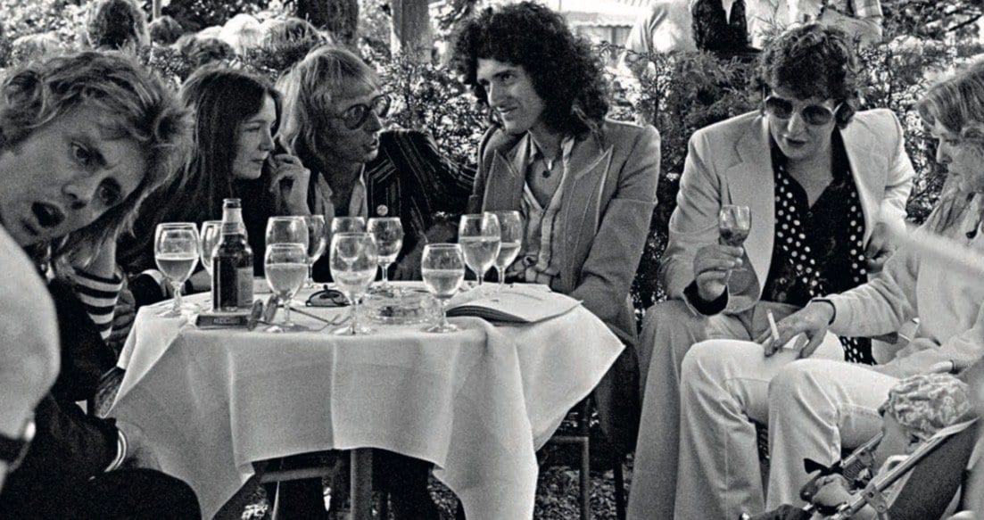 Am Tisch: Roger Taylor, Chrissy May, PR-Mann Tony Brainsby, Brian May, Produzent Roy Thomas Baker und Mary Austin (1978).